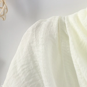 Close-up of beige crinkled cotton linen fabric showing breathable texture and raw edges
