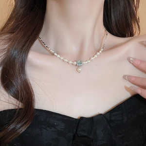 Detail of French pearl necklace with square blue gemstone pendant on a model's neck