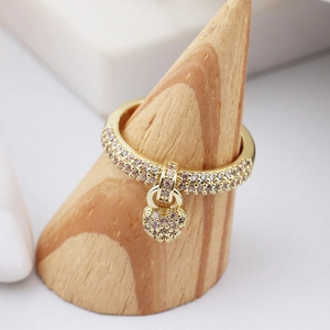 Detailed shot of a gold heart charm ring with sparkling crystals on a wooden stand