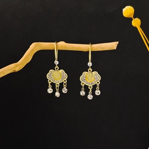 Detail of gold Ruyi lock earrings with yellow gemstone and Fu character on wood
