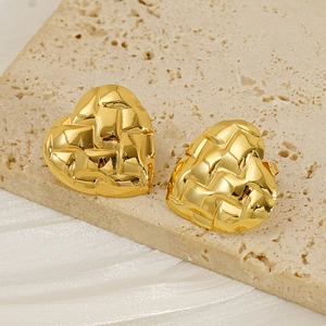 Detailed view of gold heart earrings with vintage woven texture on a stone surface