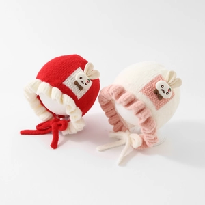 Detail of cute knitted baby bonnets with ruffled edges and rabbit patches