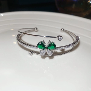 Macro di bracciale a farfalla in argento con zirconi verdi e bianchi scintillanti su porcellana