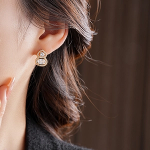 Macro shot of gold-plated gourd stud earrings with zircon crystals on female model