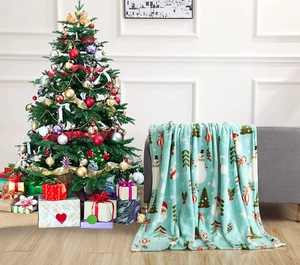 Christmas flannel blanket featuring Santa and snowman prints on a cozy sofa setting