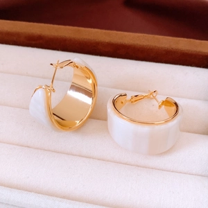 Macro shot of vintage 18K gold plated hoop earrings with white resin inlay details