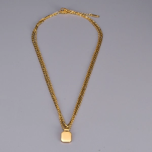 Close-up of golden double-layer chain necklace featuring a polished square pendant