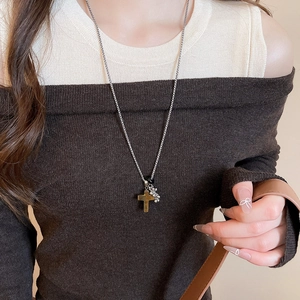 Detail of cross pendant necklace with brown textured stone and silver beaded chain on model