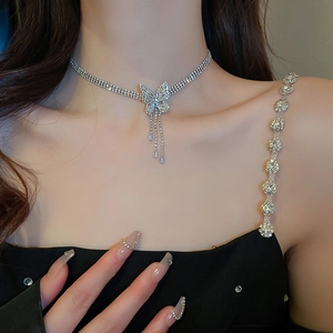 Détail du collier argenté avec pendentif papillon en zircon et pompons délicats