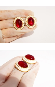Detail view of vintage-style oval earrings featuring red stones and white enamel detail