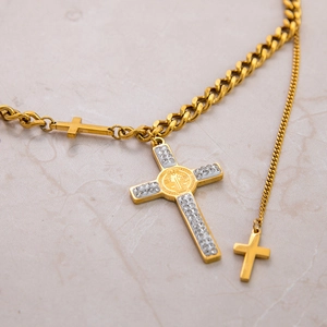 Detail of gold Cuban chain necklace with Saint Benedict cross and crystal inlay