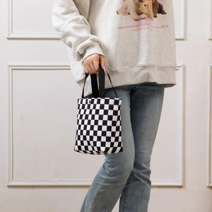 Detail of checkered canvas tote bag with black strap and secure metal snap button