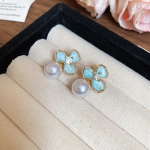 Detailed macro shot of blue enamel flower earrings with pearls in a jewelry gift box