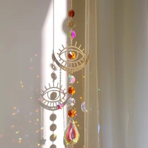 Crystal moon suncatcher wind chime with eye design reflecting rainbows on white wall
