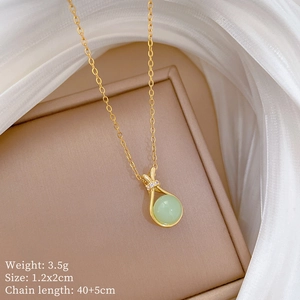 Detail view of a gold necklace with green jade pendant and diamond accents on a jewelry box