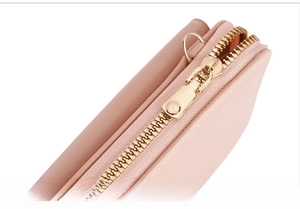 Macro detail of high-quality smooth golden copper zipper on pink lychee leather wallet