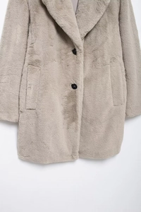 Detail of light gray faux fur coat with button closure and thick warm texture