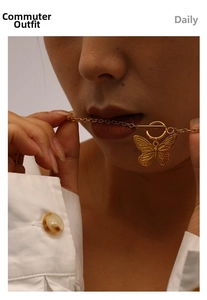 Detail of gold butterfly pendant necklace with OT toggle clasp on model wearing a white shirt
