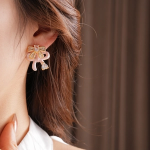 Detail of pink bow drop earrings with zircon crystals on model ear for elegant style