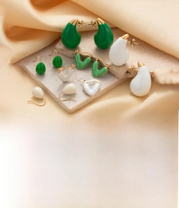Detailed view of 18K gold plated titanium water drop and heart earrings on marble base