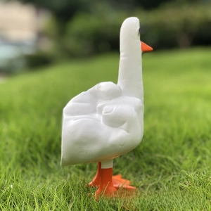 Detailed close-up of a funny white resin duck figurine with a middle finger gesture