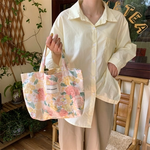 Vue détaillée du sac cabas en toile aux motifs floraux vintage et étiquette de marque en tissu