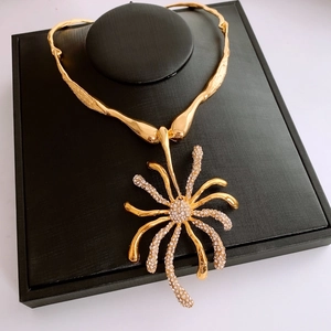 Détail macro du collier vintage doré avec pendentif fleur et strass blancs scintillants