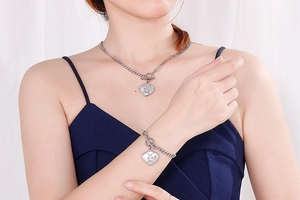 Detail of silver heart pendant with angel engraving on a toggle curb chain necklace