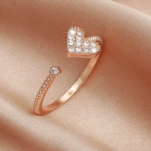 Detailed close-up of rose gold heart ring with sparkling zircons and twisted band texture