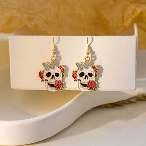 Detail of skull and red rose earrings with blue butterfly drop and golden metal base
