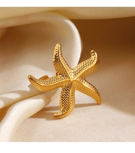 Detailed view of the gold starfish ring with unique textured grain on warm silk fabric