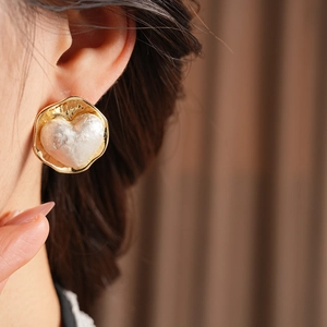 Gros plan de boucles d'oreilles cœur plaquées or 16K avec texture perle sur mannequin
