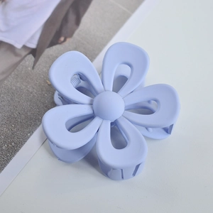 Macro view of light blue matte flower hair claw clip with a hollow five-petal design