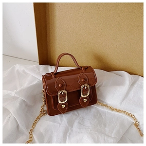 Detail view of brown patent leather mini bag with gold buckles and metal chain strap