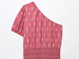 Détail d'une robe rose poudré à épaule dénudée avec imprimé floral blanc et taille élastique