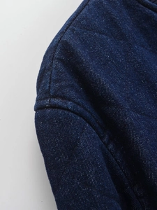 Macro view of dark blue quilted denim fabric with premium stitching on cotton coat