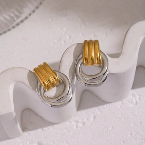 Minimalist geometric two-tone stainless steel hoop earrings on a white display stand