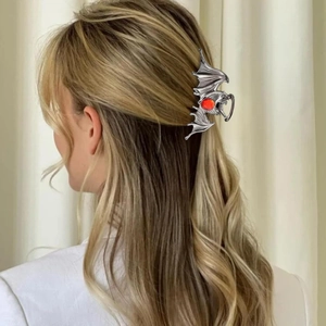 Detail of silver gothic bat hair claw with a red ruby stone on blonde hair