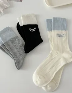 Detailed macro view of cotton rib-knit crew socks with bow and letter embroidery