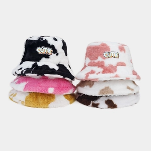 Gros plan de bobs en peluche motif vache avec des écussons brodés CUTE colorés