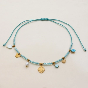 Detail of beaded necklace with blue beads, gold charms, and adjustable braided cord