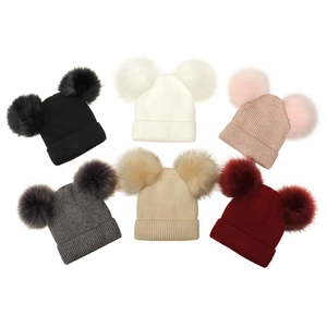 Detail view of double pom-pom knit beanies in six solid colors with ribbed texture