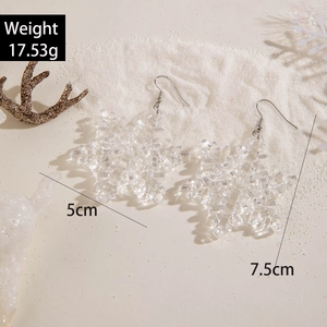 Detail of transparent snowflake resin earrings with winter corals on white sand