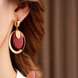 Detail of red resin oval earrings with gold-plated metal and hand made engraving