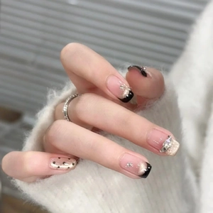 French tip press-on nails with black edges, glitter, and rhinestones on nude base