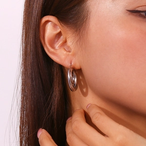 Close-up of minimalist spiral swirl earrings in polished silver on a female model