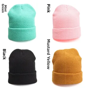 Close-up of four solid color knit beanies showing ribbed texture and wide-cuff design
