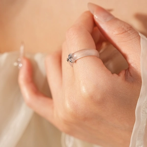 Close-up of translucent white chalcedony ring with silver metal cross and crystal