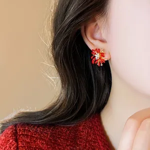 Close-up of elegant red petal stud earrings with sparkling diamonds on a model