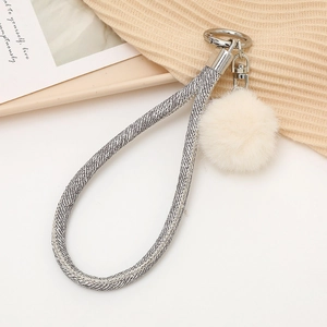 Détail du cordon pailleté gris et pompon en peluche beige avec anneau métallique